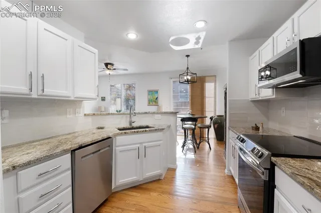 a kitchen with stainless steel appliances granite countertop a sink a stove and cabinets