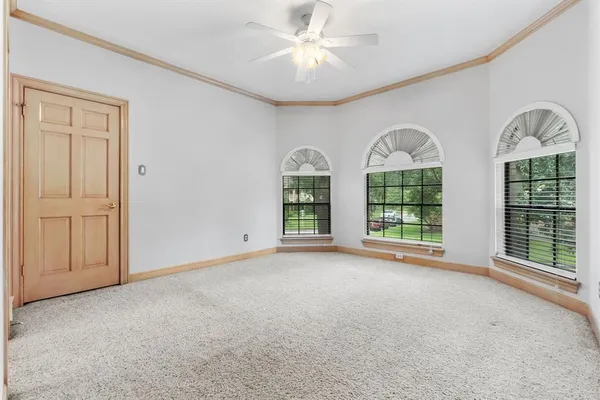 a view of an empty room with window and chandelier fan