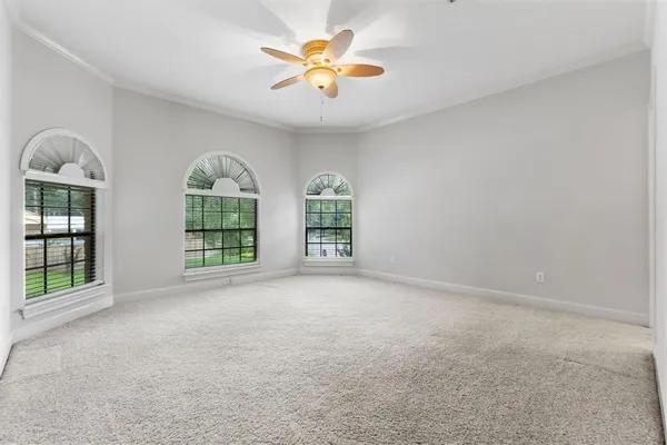 an empty room with windows and ceiling fan