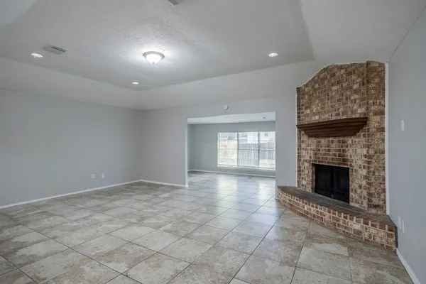 an empty room with windows and fireplace