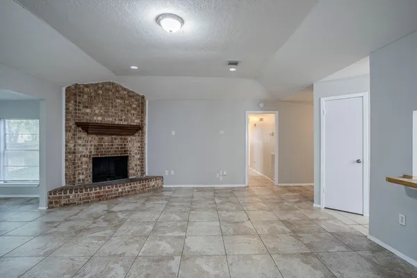 an empty room with windows and fireplace