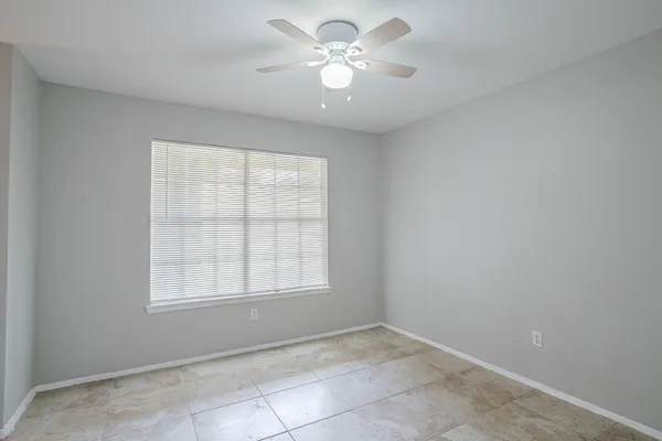 an empty room with a window and a fan