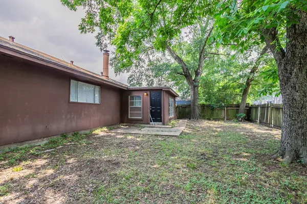 a backyard of a house with wooden fence and large trees