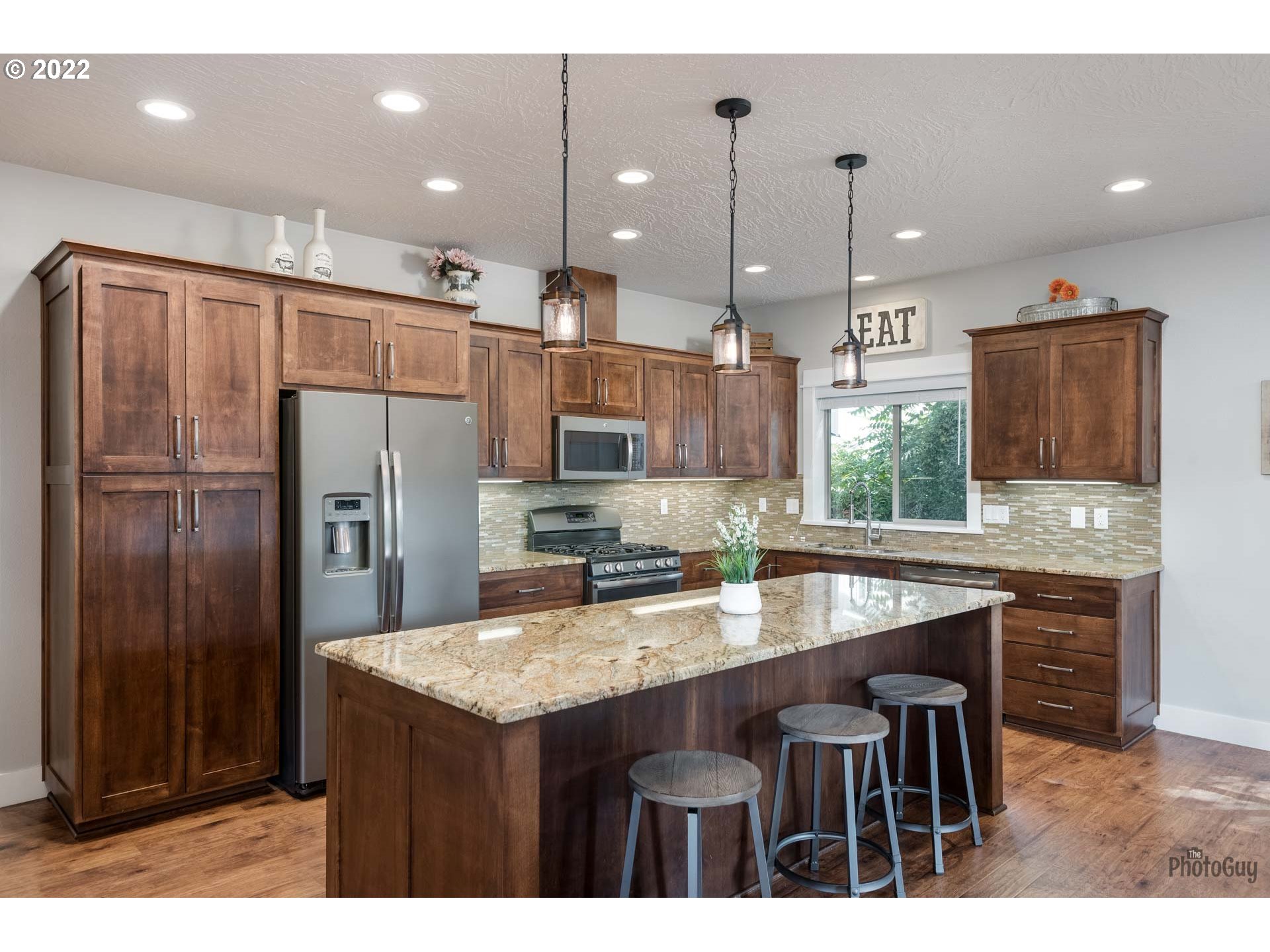 853 67th Place Springfield, OR 97478 - Photo 9 of 32 a kitchen with kitchen island a refrigerator a sink a stove and chairs