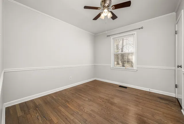 an empty room with wooden floor fan and windows