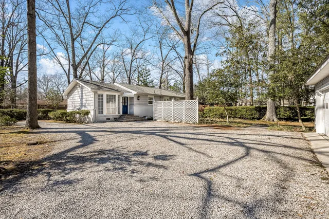 a view of a white house with a large tree