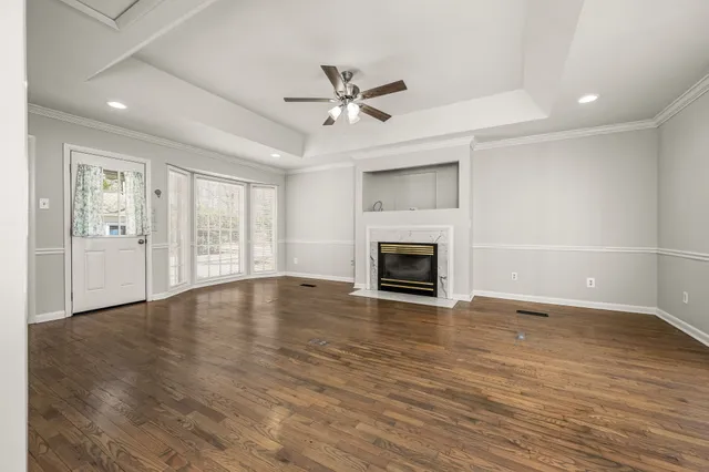 an empty room with wooden floor fireplace and windows