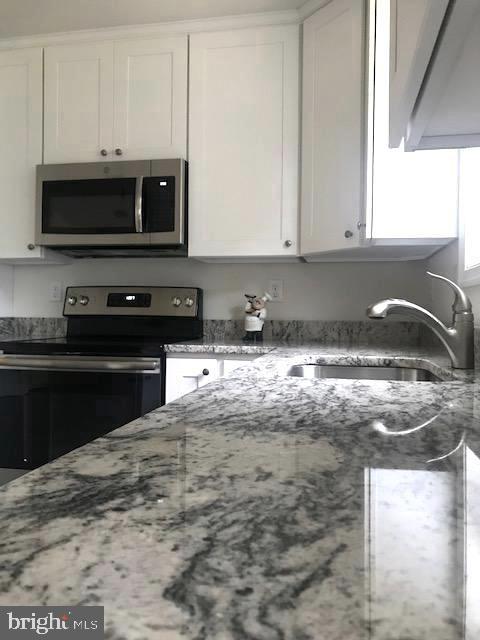 8363 WB&A Road Severn, MD 21144 - Photo 3 of 32 a kitchen with granite countertop a sink and a stove