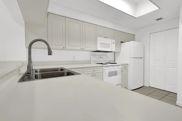 a kitchen with white cabinets and white appliances