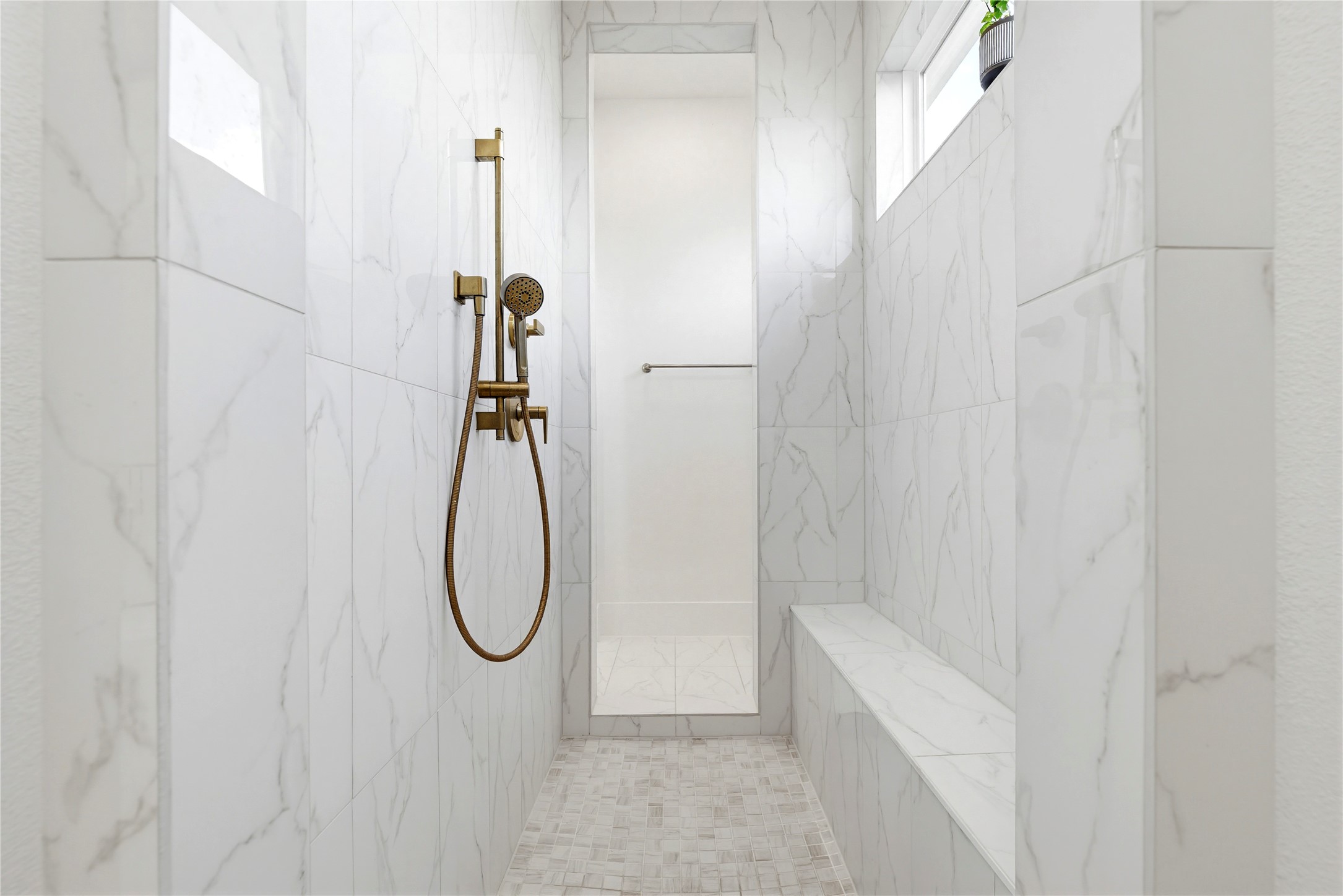 29526 Cir S Rnch Trail Fulshear, TX 77406 - Photo 21 of 47 The primary bathroom includes a separate, oversized walk-in shower finished with floor-to-ceiling marble-patterned tile and a built-in bench. This contemporary space features a rainfall showerhead and upgraded gold hardware, maintaining the home's high-end aesthetic.