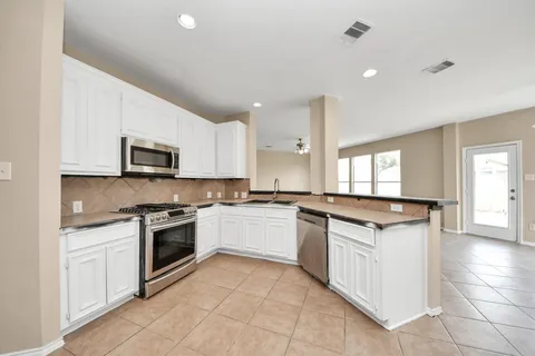a kitchen with granite countertop white cabinets and appliances