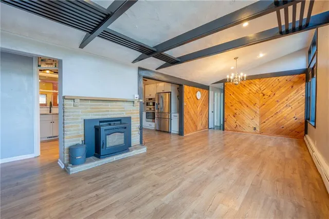 a view of an empty room with wooden floor fireplace and a window