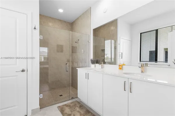 a bathroom with a double vanity sink mirror and shower