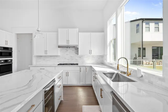 a kitchen with granite countertop a sink stainless steel appliances and white cabinets