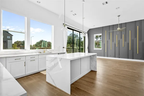 a large white kitchen with granite countertop a large window and white appliances