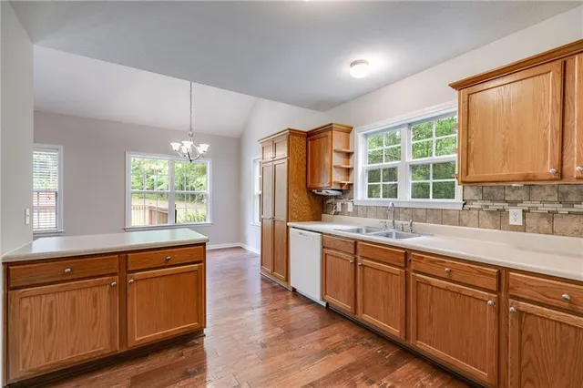 a kitchen with wooden floors wooden cabinets a sink and a window