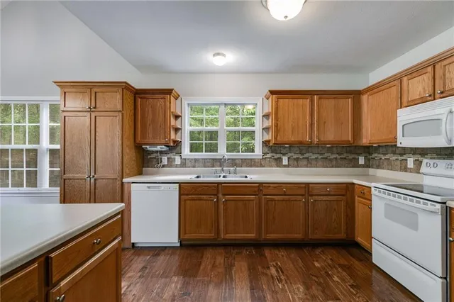 a kitchen with stainless steel appliances granite countertop a stove a sink dishwasher a refrigerator and white cabinets with wooden floor