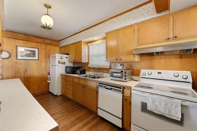 a kitchen that has a lot of white cabinets and stainless steel appliances