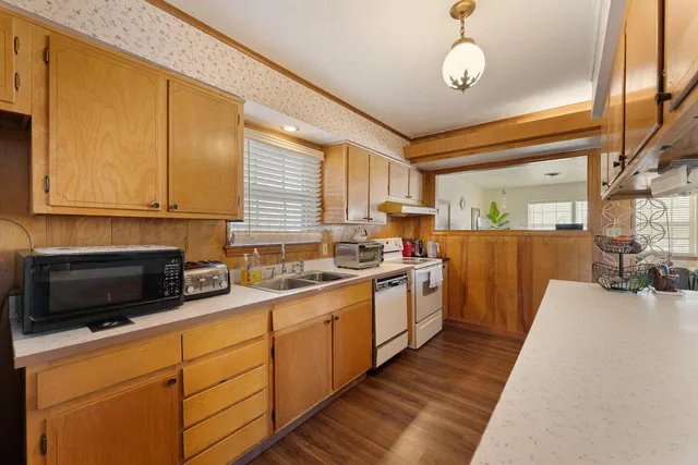 a kitchen with stainless steel appliances granite countertop wooden cabinets a stove top oven a sink and dishwasher
