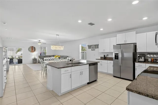 a kitchen with stainless steel appliances granite countertop a sink a stove a microwave a refrigerator and white cabinets