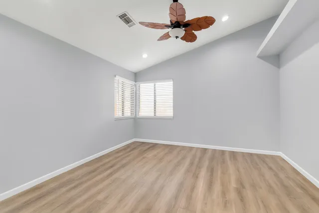 an empty room with a window and a ceiling fan