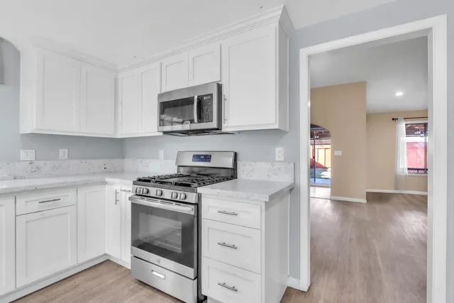a kitchen with cabinets stainless steel appliances and wooden floor