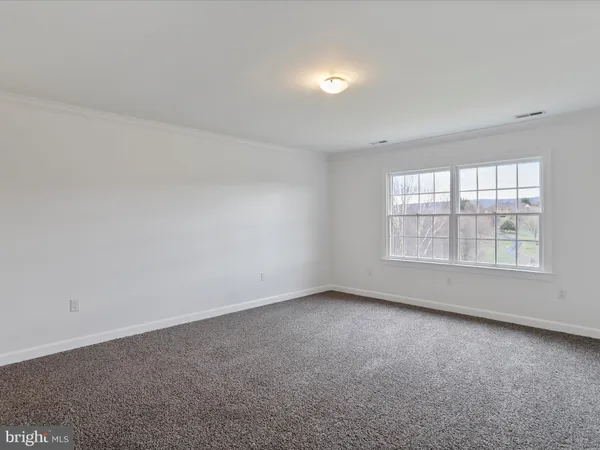 a view of an empty room with wooden floor and windows