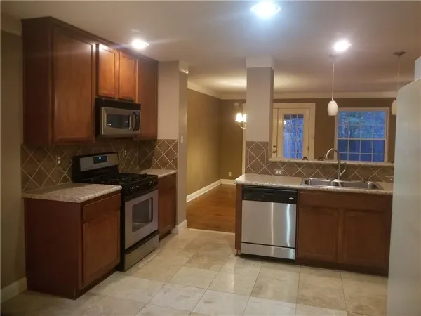 a kitchen with stainless steel appliances granite countertop a stove a sink and a microwave