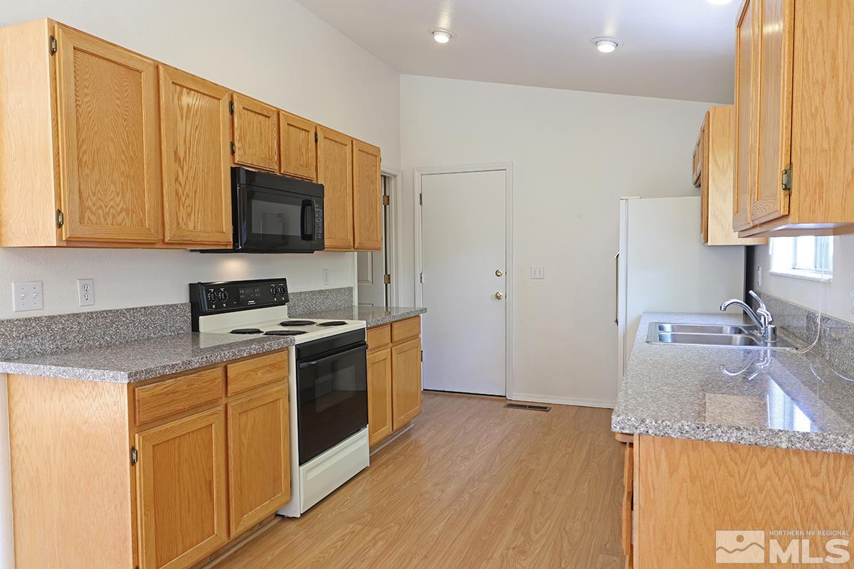 4652 Goodwin Road Sparks, NV 89436 - Photo 7 of 20 a kitchen with granite countertop a sink a stove top oven and cabinetry