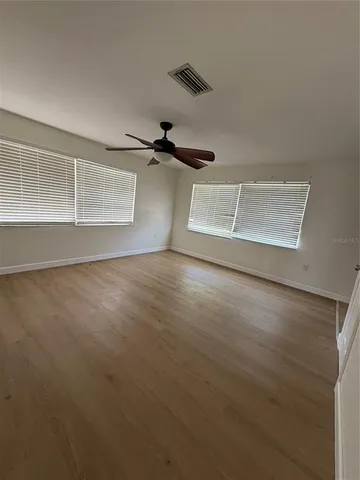 an empty room with wooden floor cabinet and windows