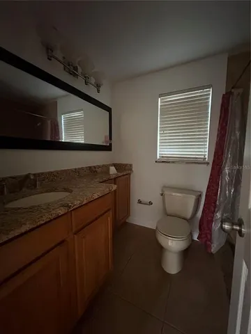 a bathroom with a granite countertop toilet sink and mirror