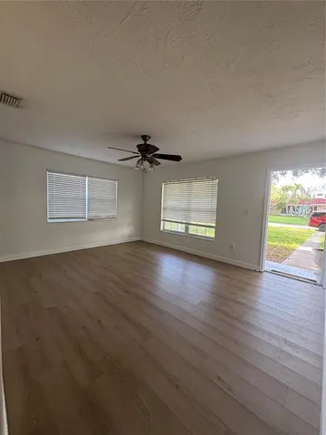 an empty room with wooden floor and windows