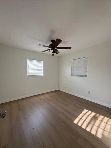 a view of empty room with wooden floor and fan