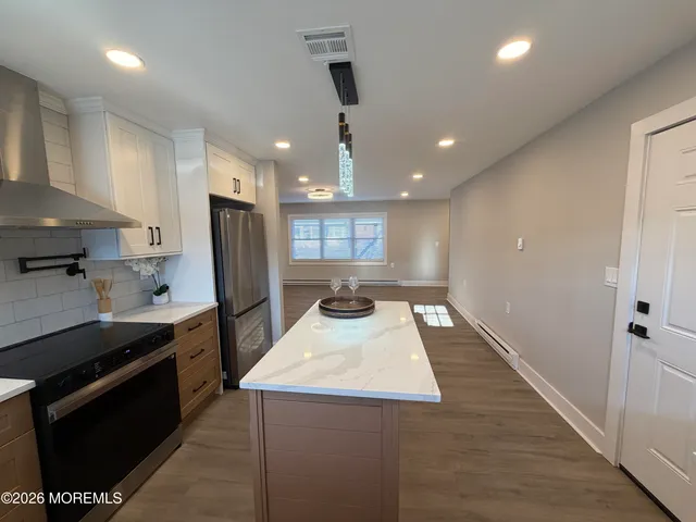 a kitchen with kitchen island a counter space a stove a refrigerator and a sink