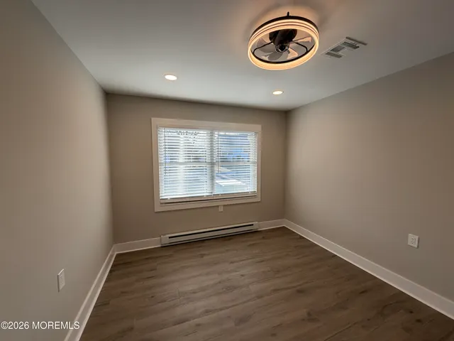 an empty room with wooden floor and window