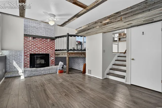 a view of a livingroom with wooden floor and a fireplace