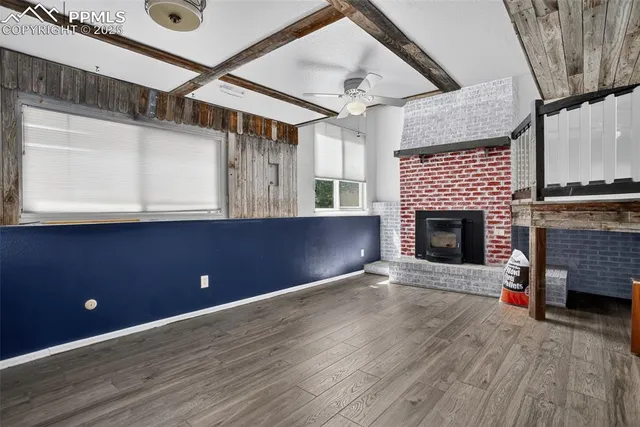 a view of an empty room with wooden floor and a fireplace