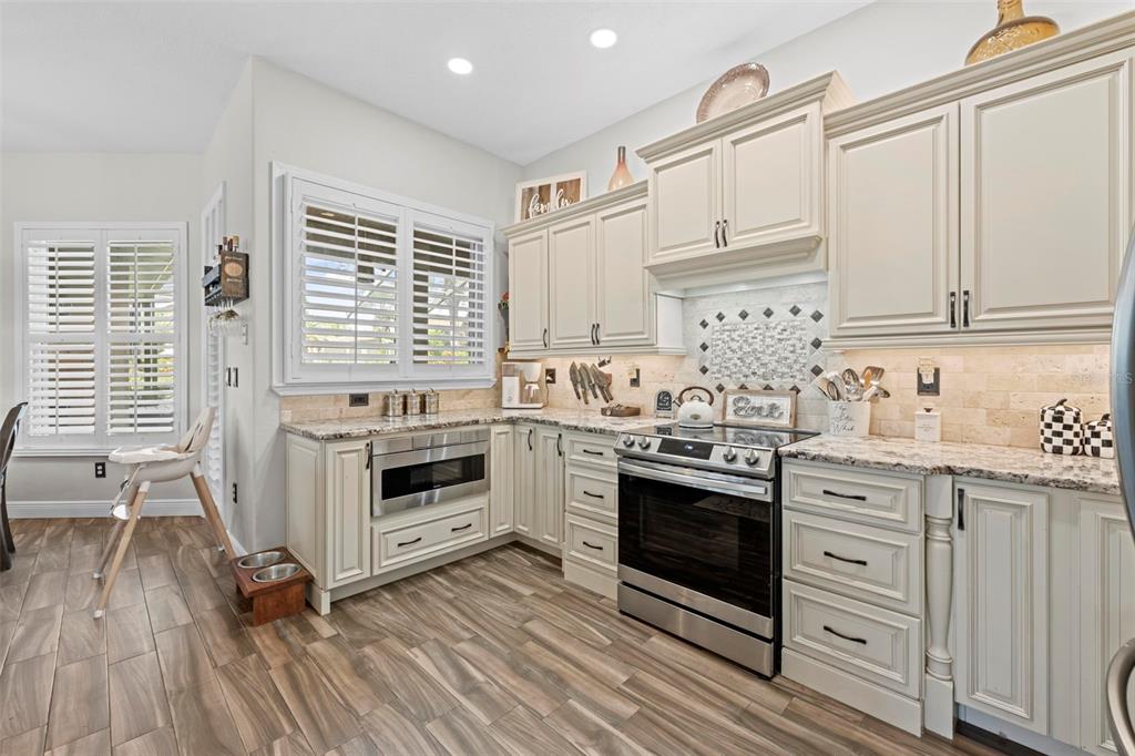 14173 Pullman Drive Spring Hill, FL 34609 - Photo 45 of 77 a kitchen with stainless steel appliances granite countertop a stove and white cabinets