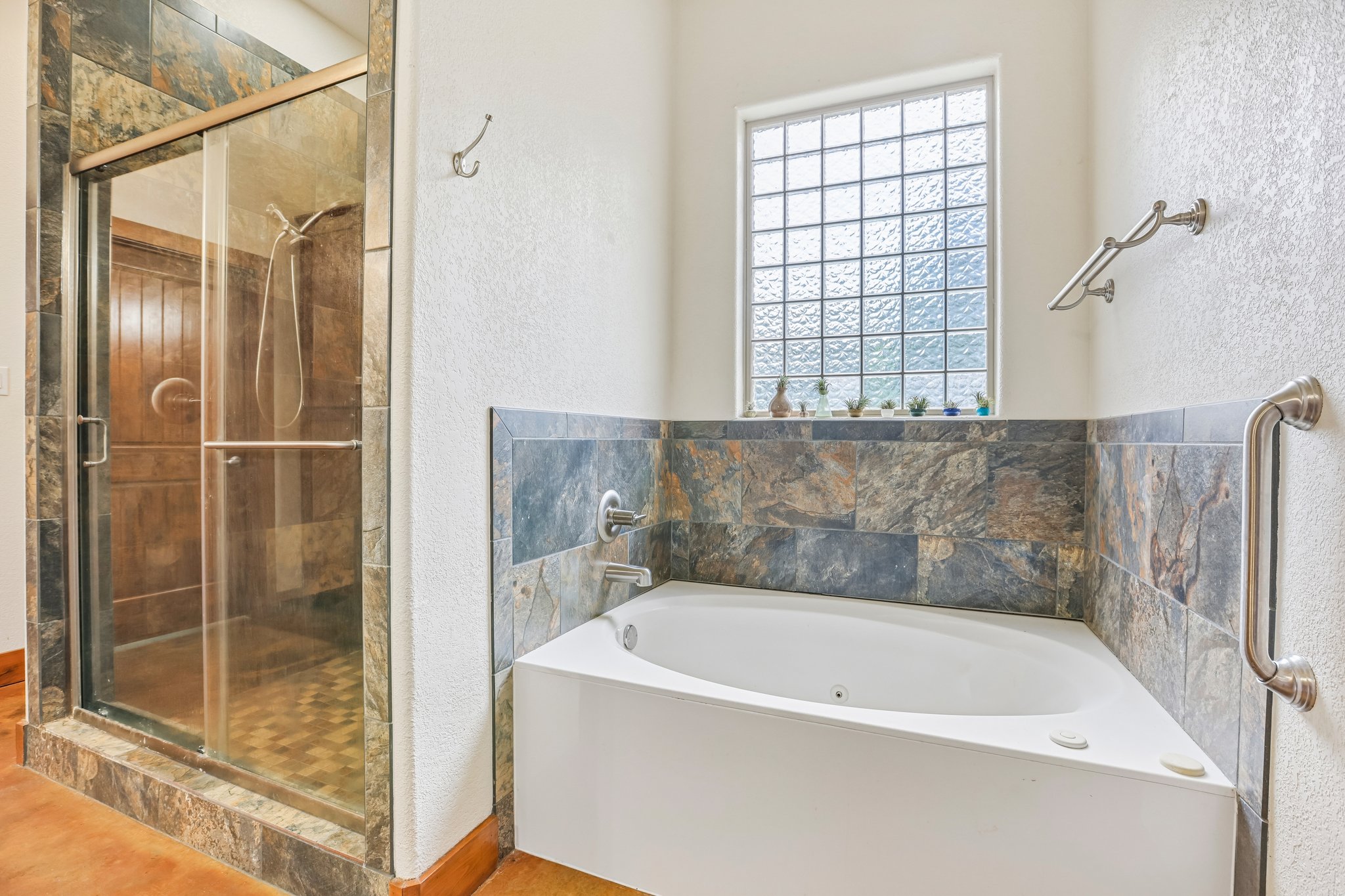 267 Corral Road Smithville, TX 78957 - Photo 32 of 40 Corner soaking tub featuring a stone tile surround and a glass block window