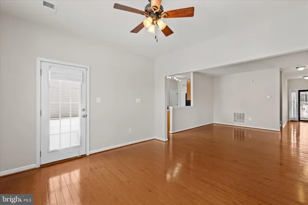 a view of an empty room with window and wooden floor