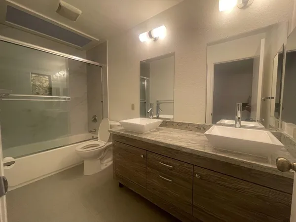 a bathroom with a granite countertop sink a toilet and shower