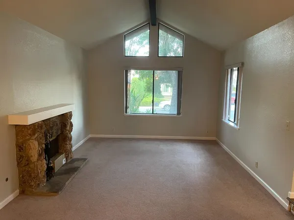 an empty room with windows and fireplace