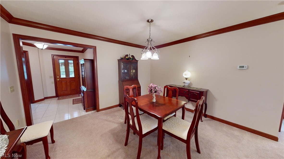 167 Mathews Road, Unit B Youngstown, OH 44512 - Photo 9 of 34 Dining area with light colored carpet, a chandelier, and crown molding