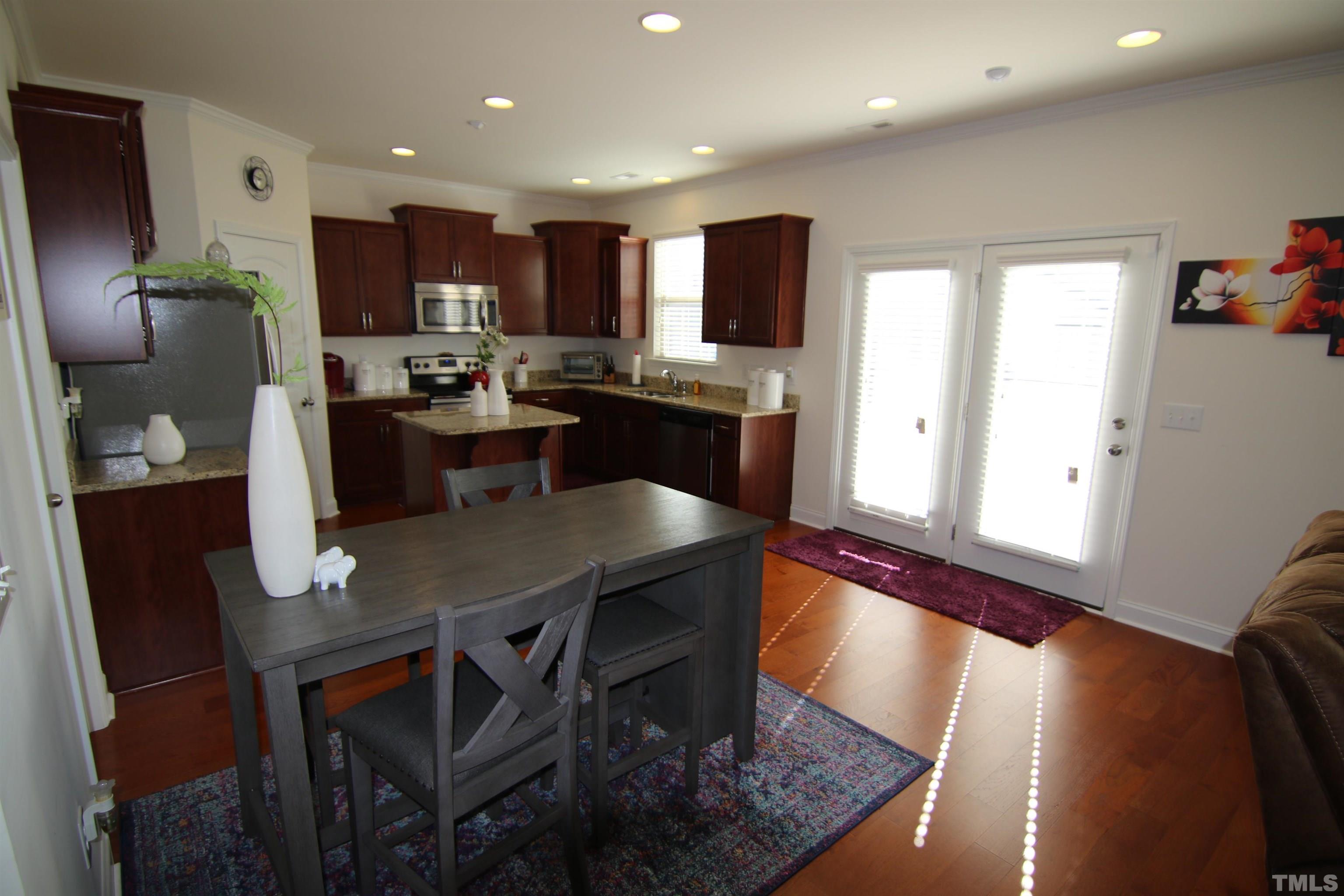 3216 Revelation Street Raleigh, NC 27610 - Photo 9 of 23 a kitchen with stainless steel appliances granite countertop a table chairs refrigerator a sink a stove a microwave and dining table