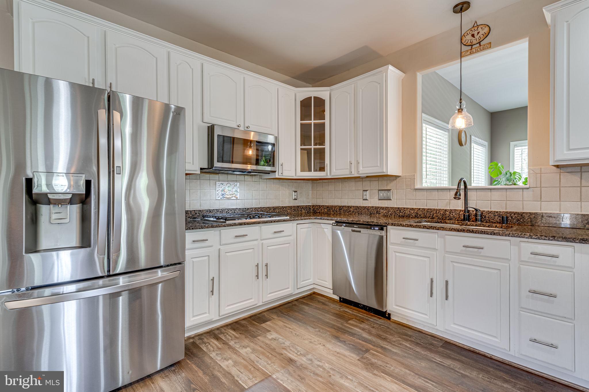 6904 North Stuart Road King George, VA 22485 - Photo 12 of 47 a kitchen with stainless steel appliances granite countertop a refrigerator sink and white cabinets