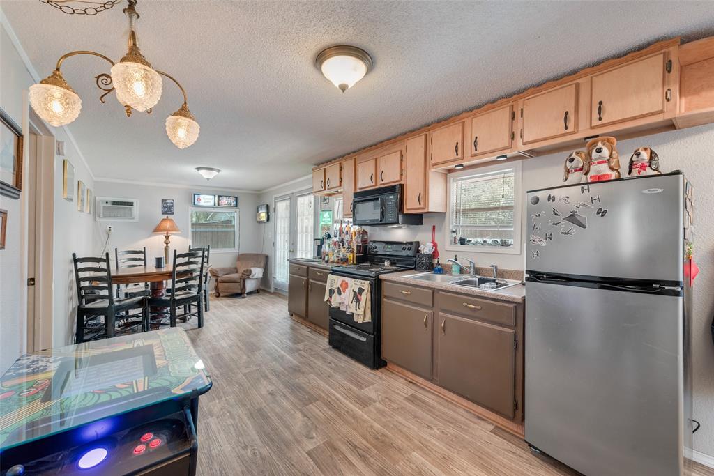 233 East High Street Wills Point, TX 75169 - Photo 22 of 35 Kitchen with black appliances, light wood-style floors, pendant lighting, a textured ceiling, and light countertops