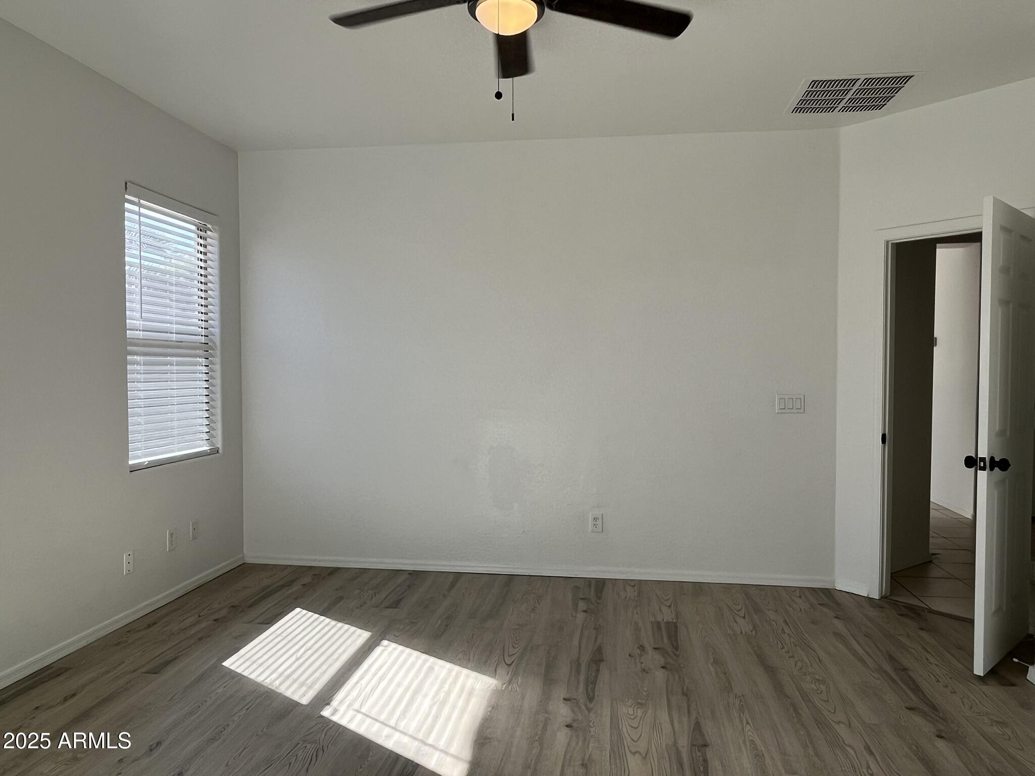 2319 West Alta Vista Road Phoenix, AZ 85041 - Photo 26 of 43 an empty room with wooden floor cabinet and windows
