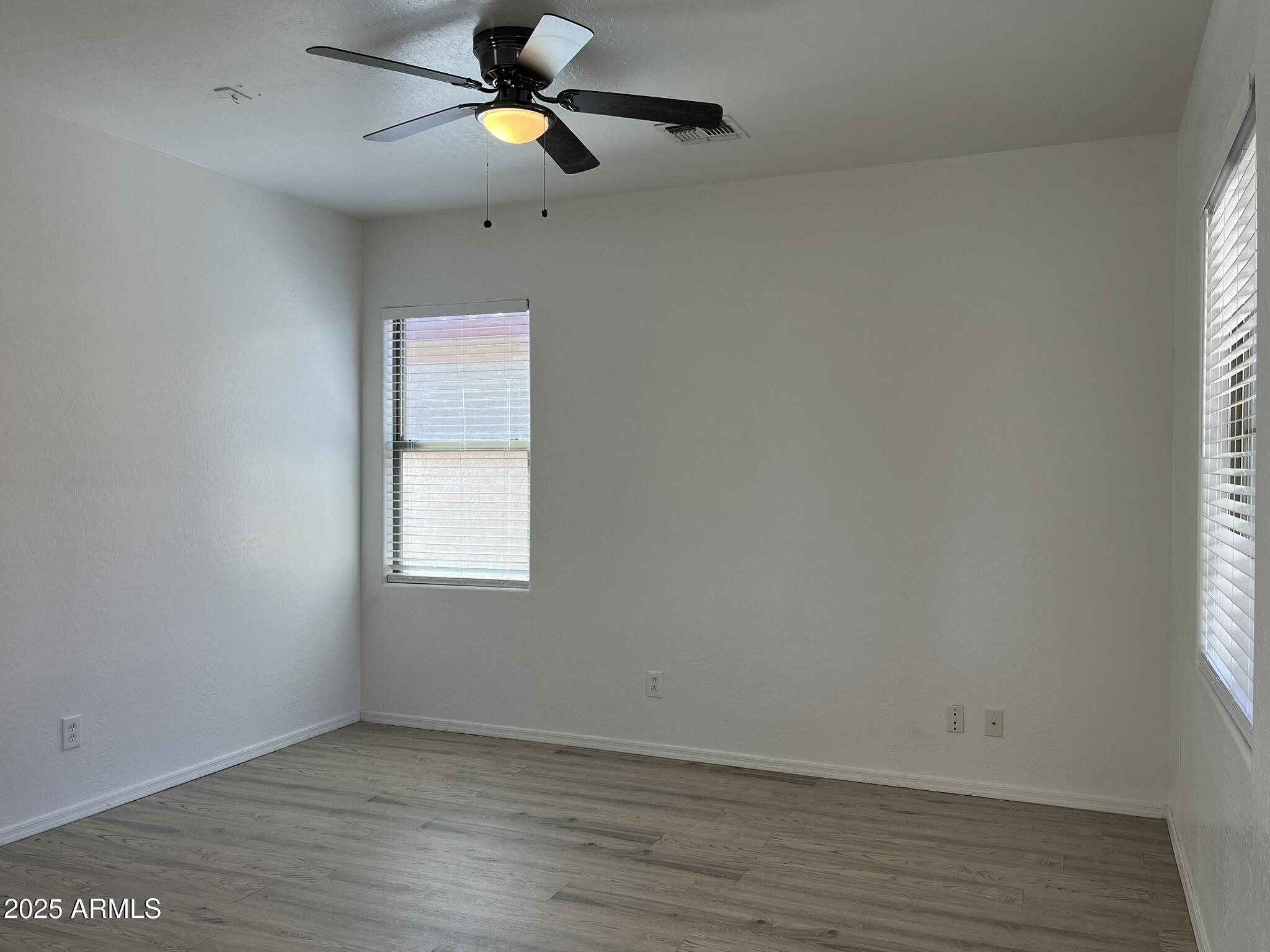 2319 West Alta Vista Road Phoenix, AZ 85041 - Photo 5 of 43 an empty room with wooden floor a ceiling fan and window