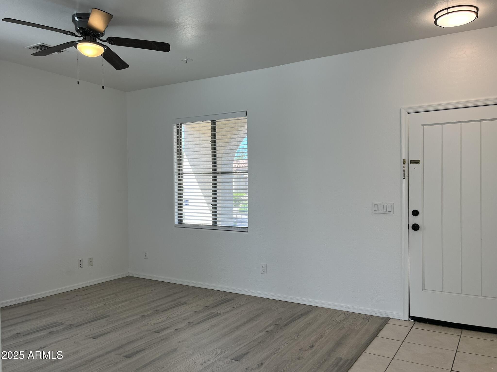 2319 West Alta Vista Road Phoenix, AZ 85041 - Photo 7 of 43 an empty room with wooden floor fan and windows