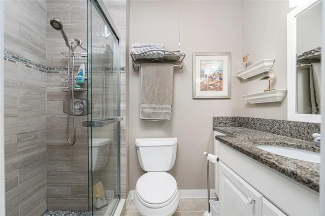 a bathroom with a granite countertop toilet a sink and shower